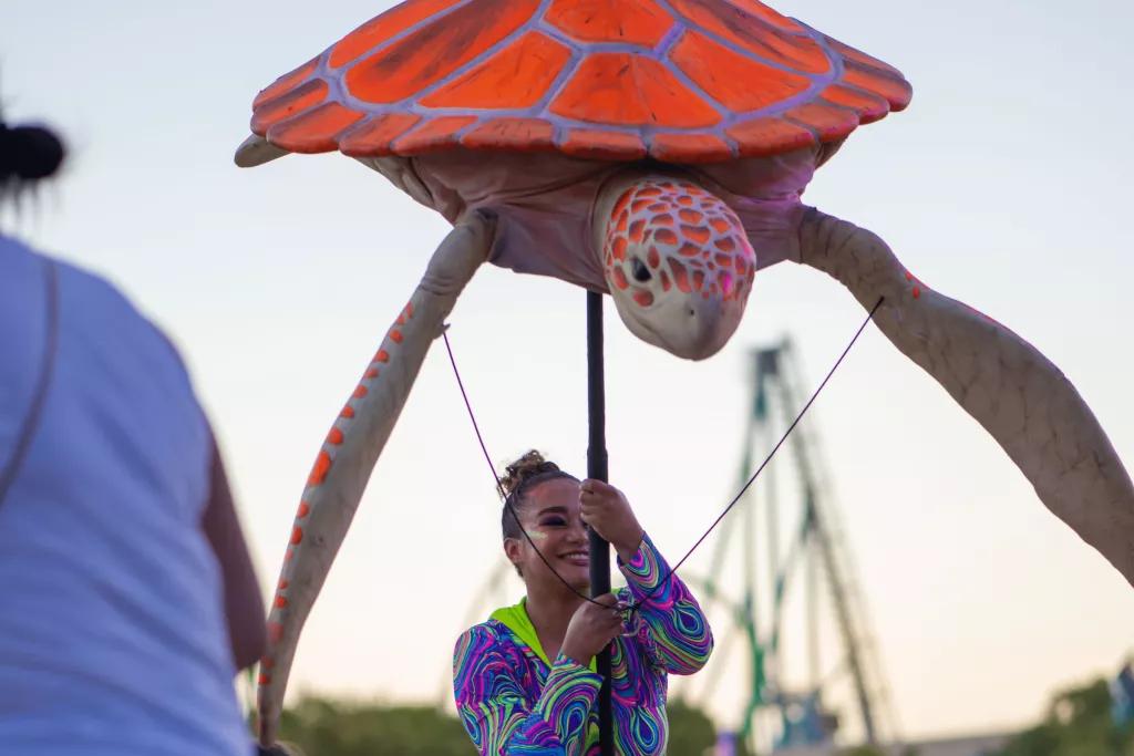 SeaWorld Summer Spectacular A female performer in a neon top holding a large sea turtle puppet above her head