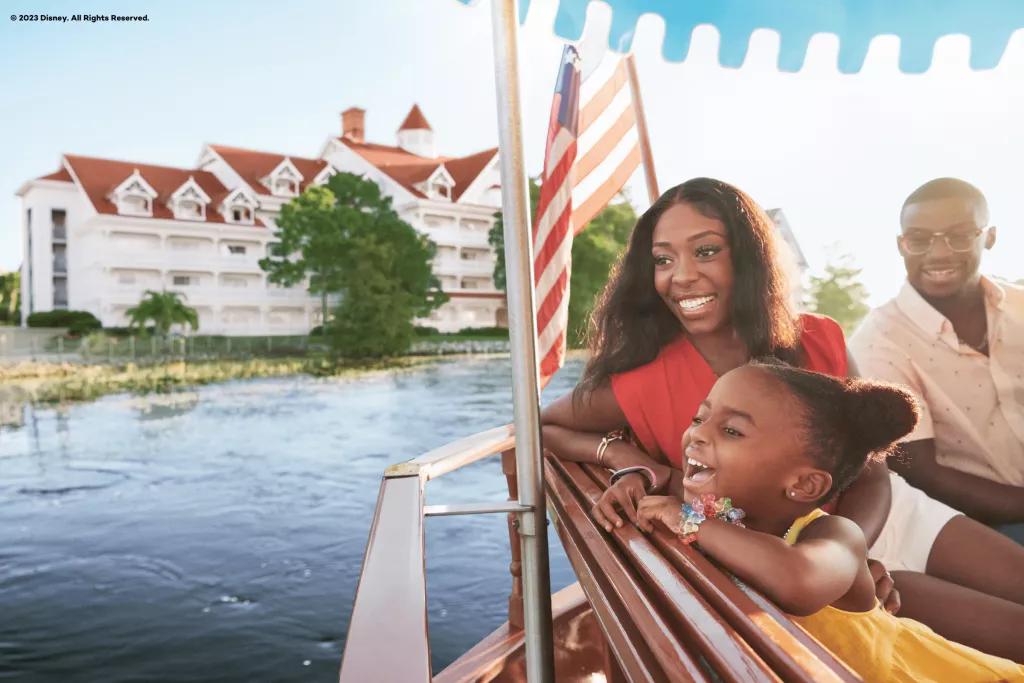 Boat Transportation at Walt Disney World Resort A man, woman and young children sat in a boat looking out over a lake with a large Victorian style building behind them