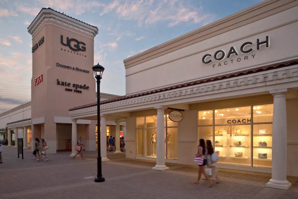 Orlando Premium Outlets The exterior of a Coach outlet store with two people walking outside
