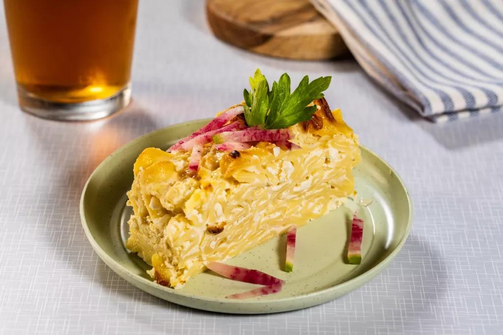 Egg Noodle Kugel A plate of egg noodle kugel in front of a pint of beer