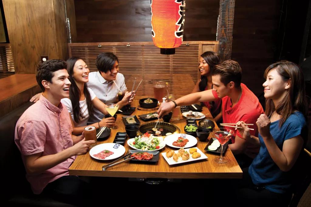 Magical Dining A group of friends sat round a table eating Japanese food