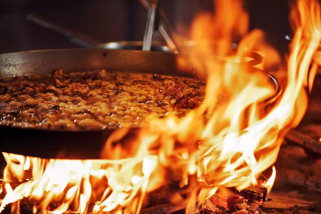 JALEO at Disney Springs A large pan of paella being cooked over an open flame