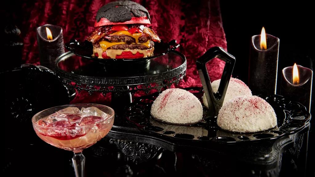 Food and Drink at Halloween Horror Nights 2023 Snowball cakes, a double cheeseburger with a red bun and a cocktail against a black and red background