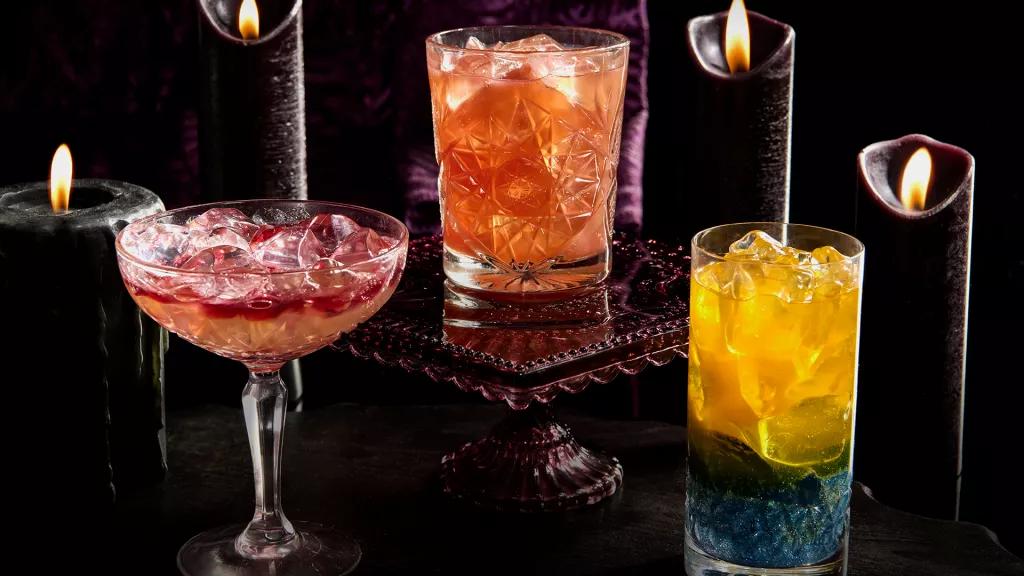 Cocktails and Mocktails at Halloween Horror Nights Three colourful cocktails in front of 4 black candles