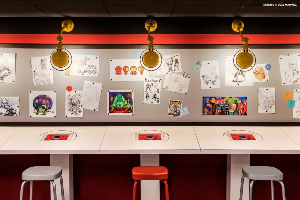 Marvel Design Studio A row of desks against a wall covered in cartoon drawings of Marvel characters