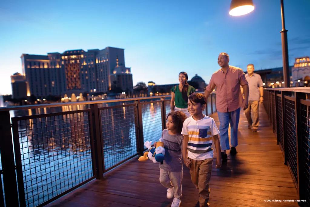 Visiting Coronado Springs Resort A family walking along a wooden bridge with Coronado Springs in the background