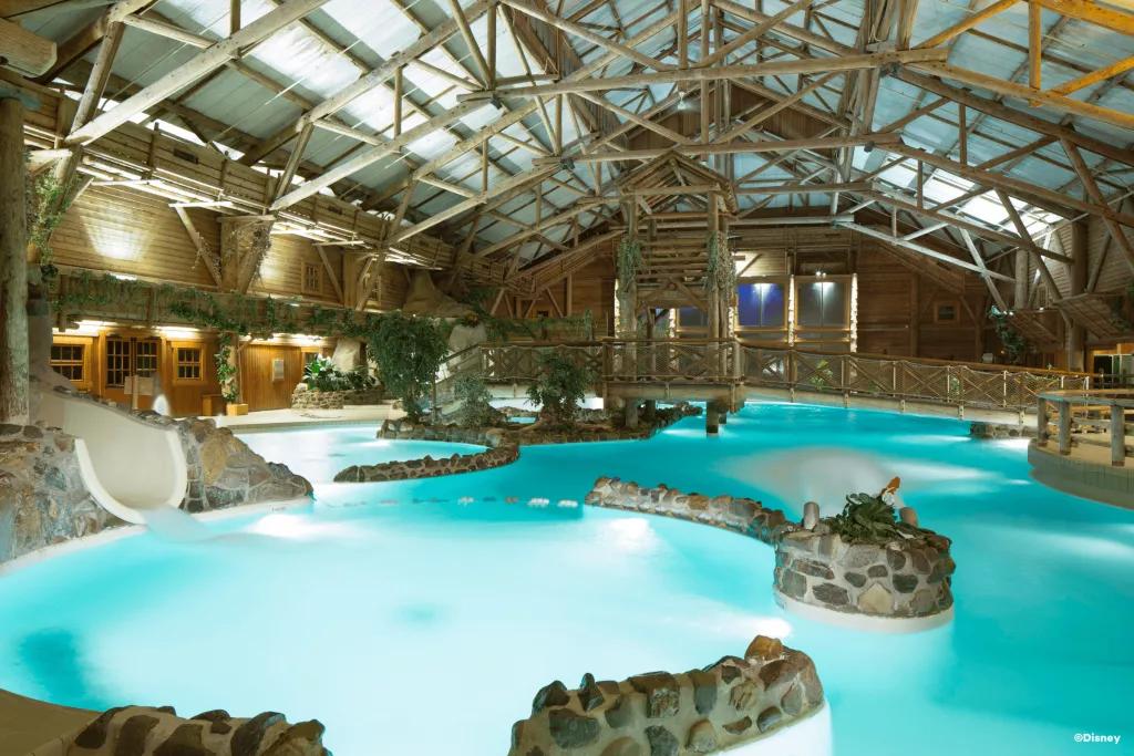 The Pool at Disney Davy Crockett Ranch An indoor pool decorated with rocks, greenery and wooden accents
