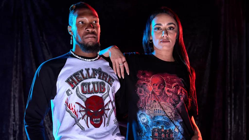 Stranger Things Apparel A man wearing a Hellfire Club tshirt and a woman wearing a Stranger Things 4 tshirt