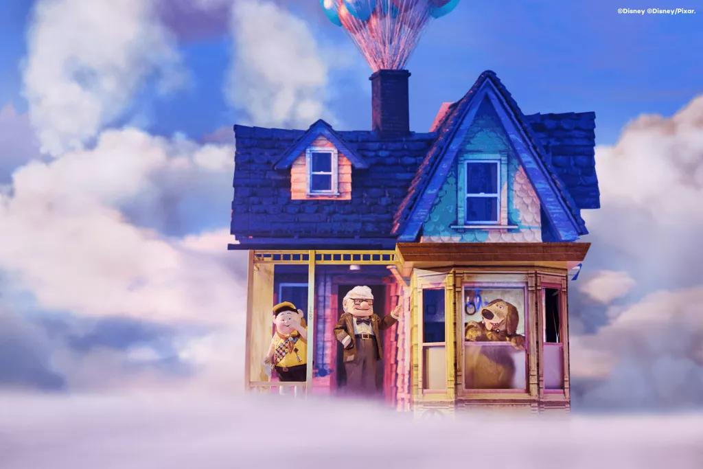 Stage Shows at Disneyland Paris Carl, Russel, and Dug standing in front of a multicoloured house on a stage covered with fog