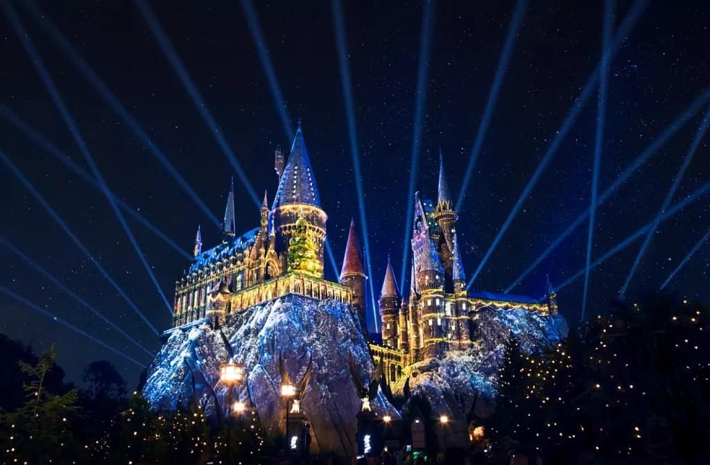 The Magic of Christmas at Hogwarts Castle Hogwarts Castle lit up in the dark with yellow and blue projections