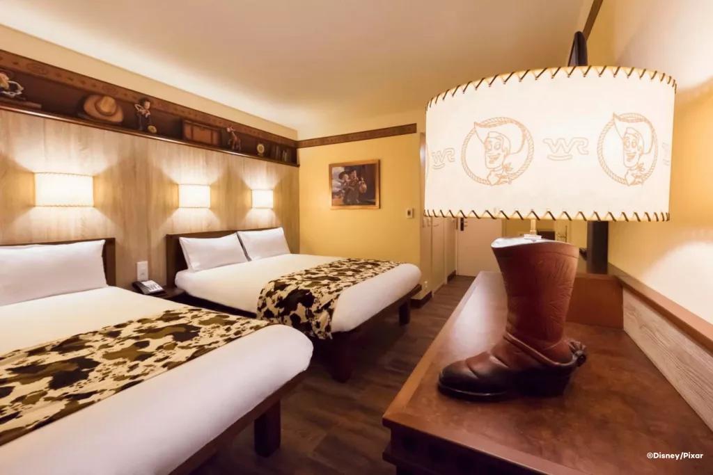 Toy Story-themed rooms at Disney Hotel Cheyenne A Toy Story themed hotel room with two double beds in the background and a lamp shaped like a cowboy boot in the foreground
