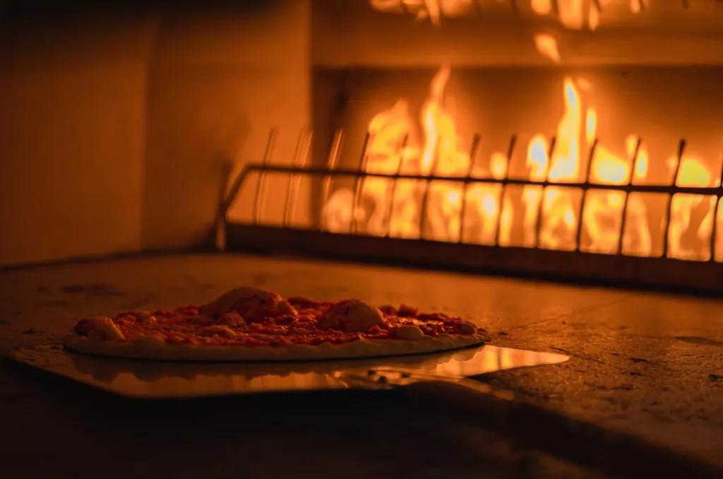 Pizza in Orlando A thin crust pizza being put into a pizza oven with flames in the background
