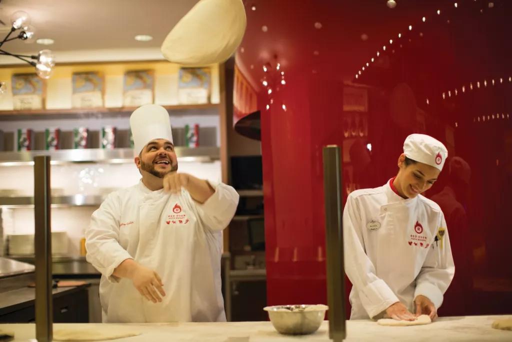 Red Oven Pizza Bakery Two chefs standing at a bench tossing pizza dough