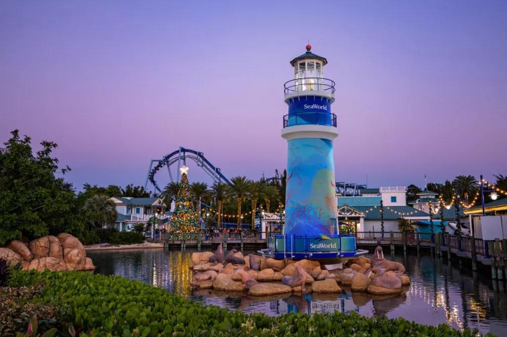 Christmas at SeaWorld The SeaWorld lighthouse in front of a purple tinted sky and a lit up Christmas tree