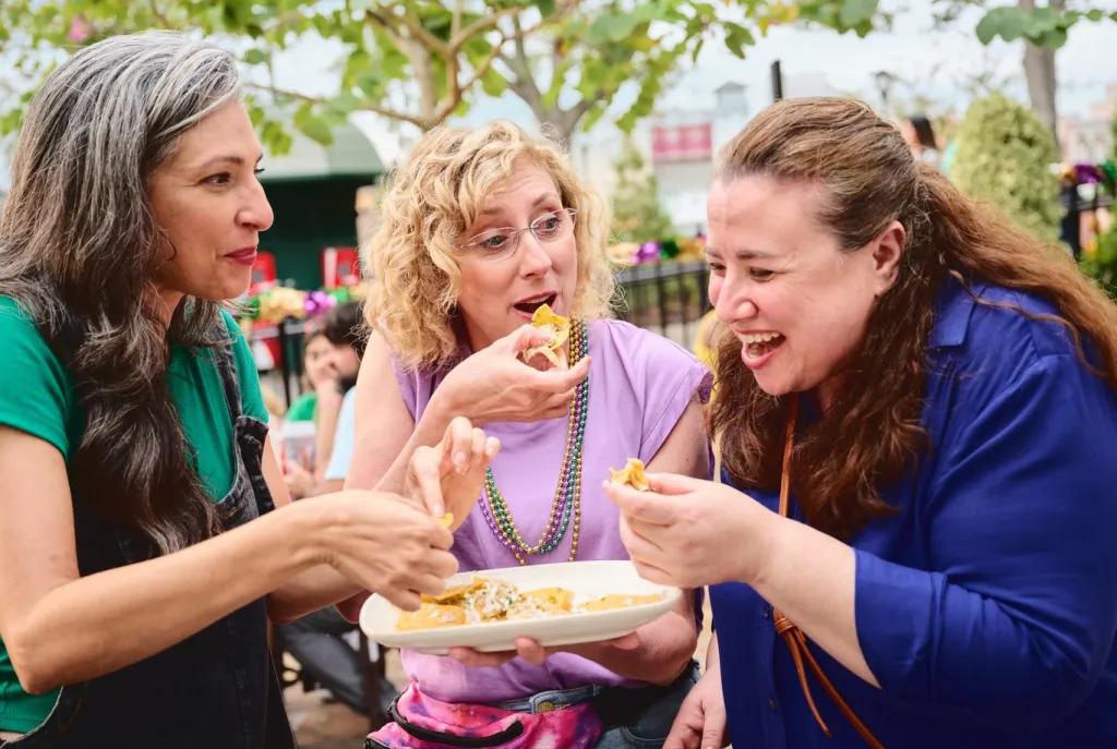Mardi Gras at Universal Orlando Resort Three women laughing while sharing a plate of food