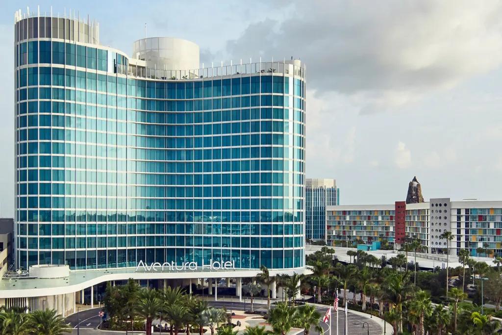 Universal's Aventura Hotel A tall hotel covered in glass panels with a rooftop bar on top