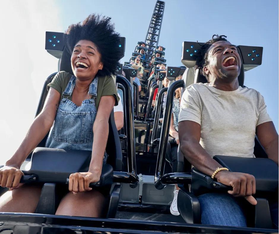 Jurassic World VelociCoaster Two people laughing and smiling sat on a rollercoaster after track turned upside down