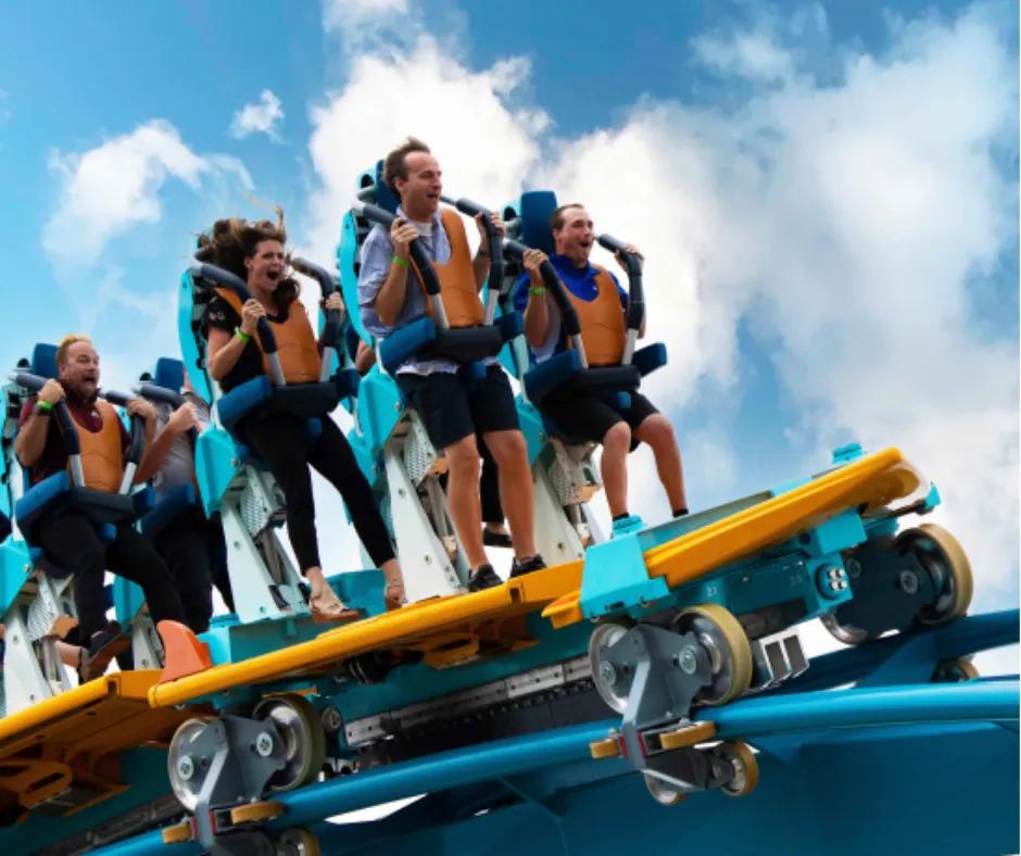 Pipeline: The Surf Coaster in SeaWorld Orlando Roller coaster car on track shaped like a surfboard in turquoise and orange colours, riders are stood up with harness over their shoulders