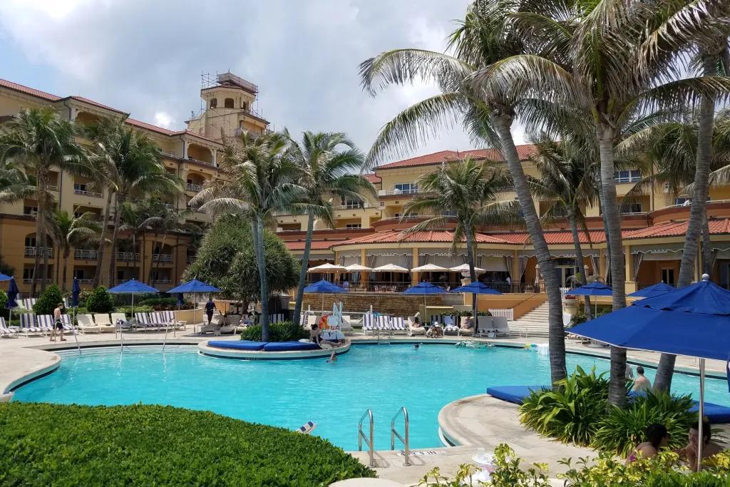 A hotel pool surrounded by palm trees and sun loungers