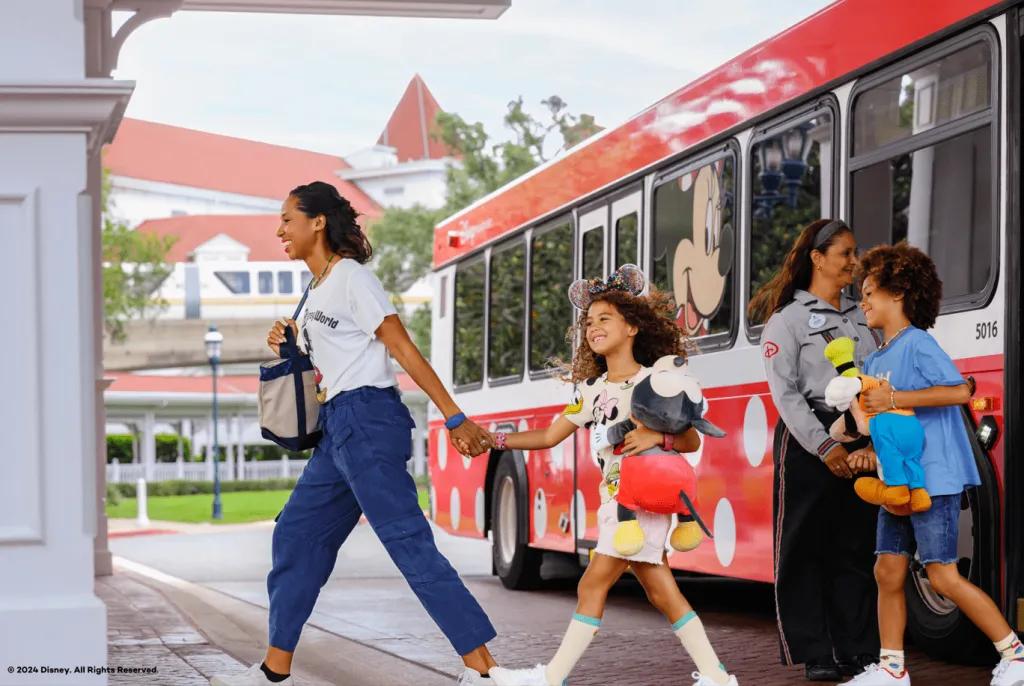 Free Transportation at Disney Resort hotels A woman leading a young girl and young boy off a bus decorated with polka dots