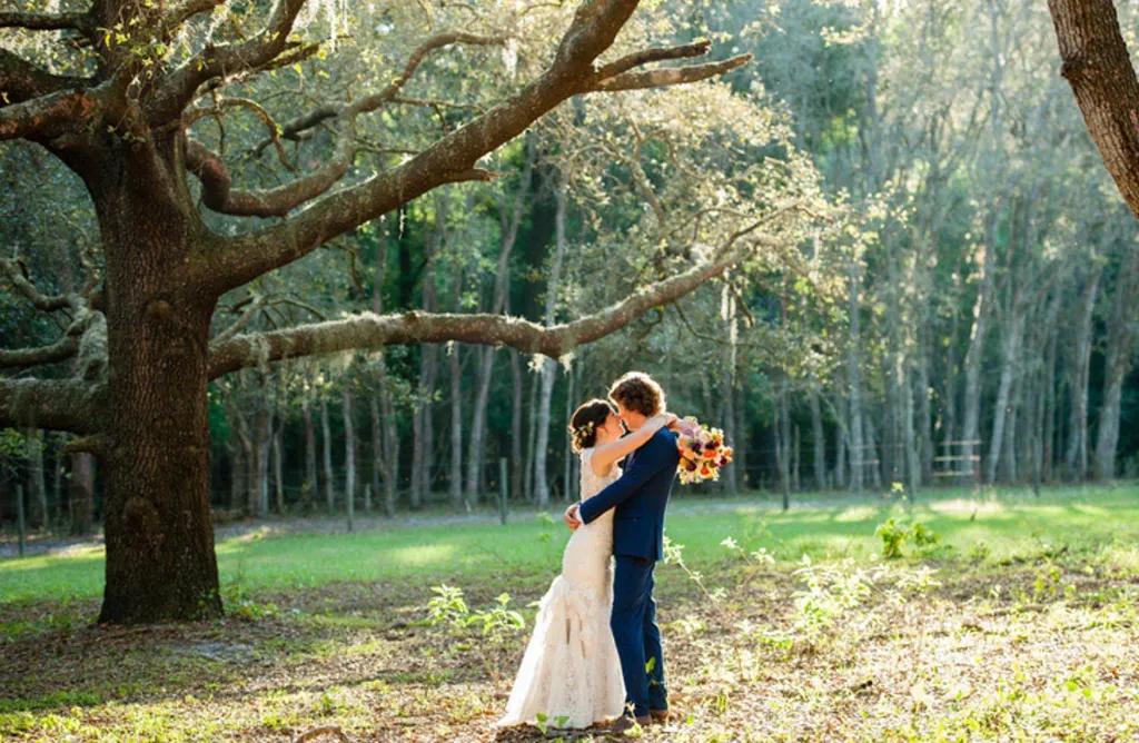 Orlando Weddings A bride and groom kissing each other while standing underneath a large tree