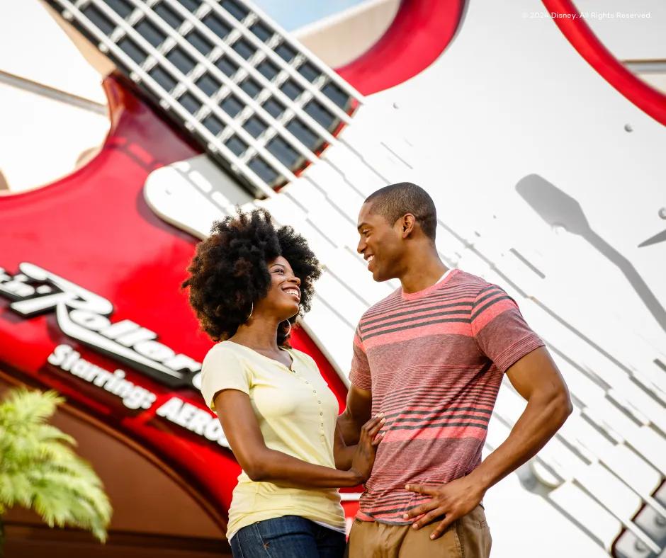 Rock 'n' Roller Coaster Starring Aerosmith Couple stood in front of beige building with giant red guitar on the front with white strings and the name of the ride on the bottom left