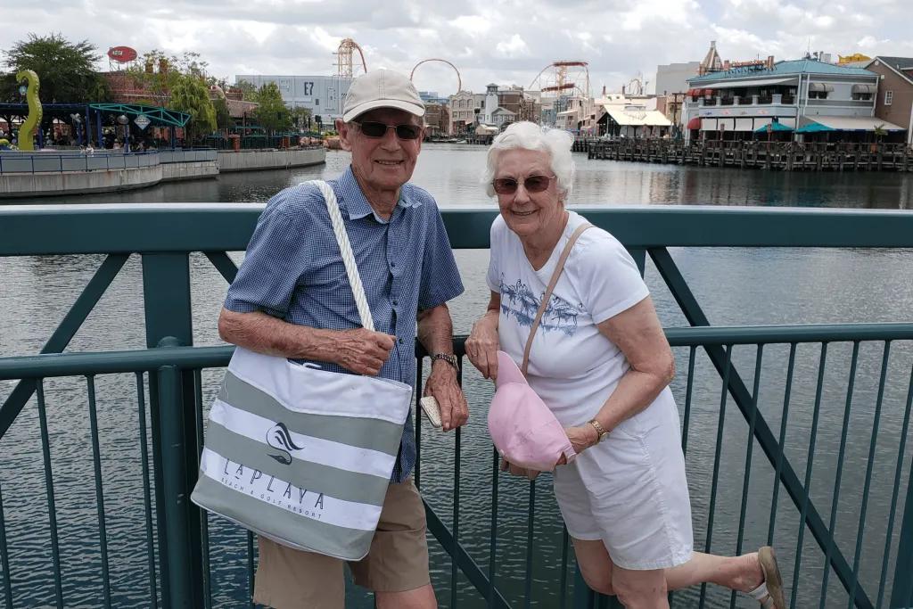 Universal Studios An older couple posing in front of a lake with a theme park in the background