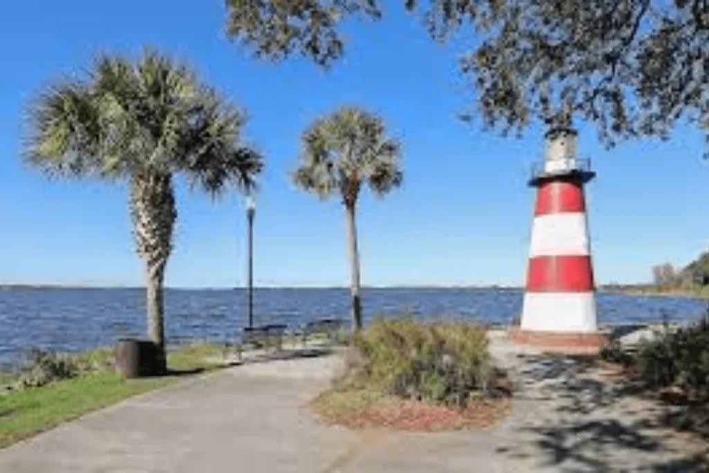 Lake Dora A white and red striped lighthouse and palm trees in front of a lake