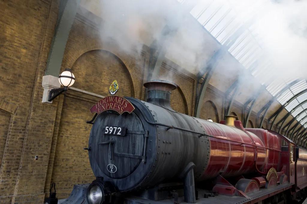The Hogwarts Express Red and black train with steam coming out of its funnel is still in a brick station. On the front it says "Hogwarts Express"