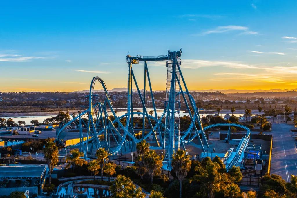 Emperor in SeaWorld San Diego Large light blue rollercoaster with steep drop and inversions. In the background there is a blue sky with a hint of orange sunset.