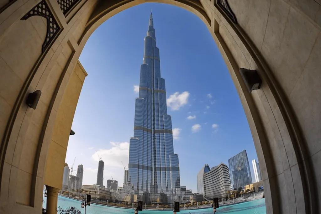 The Burj Khalifa A view of the Burj Khalifa tower through an archway and below there is a river. The Burj Khalifa is the world's tallest building made purely of glass windows in a triangle shape.