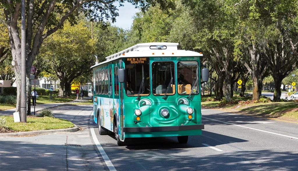 The I-Ride Trolley A green bus driving on a road with a cartoon face on the front smirking and looking off to the side.