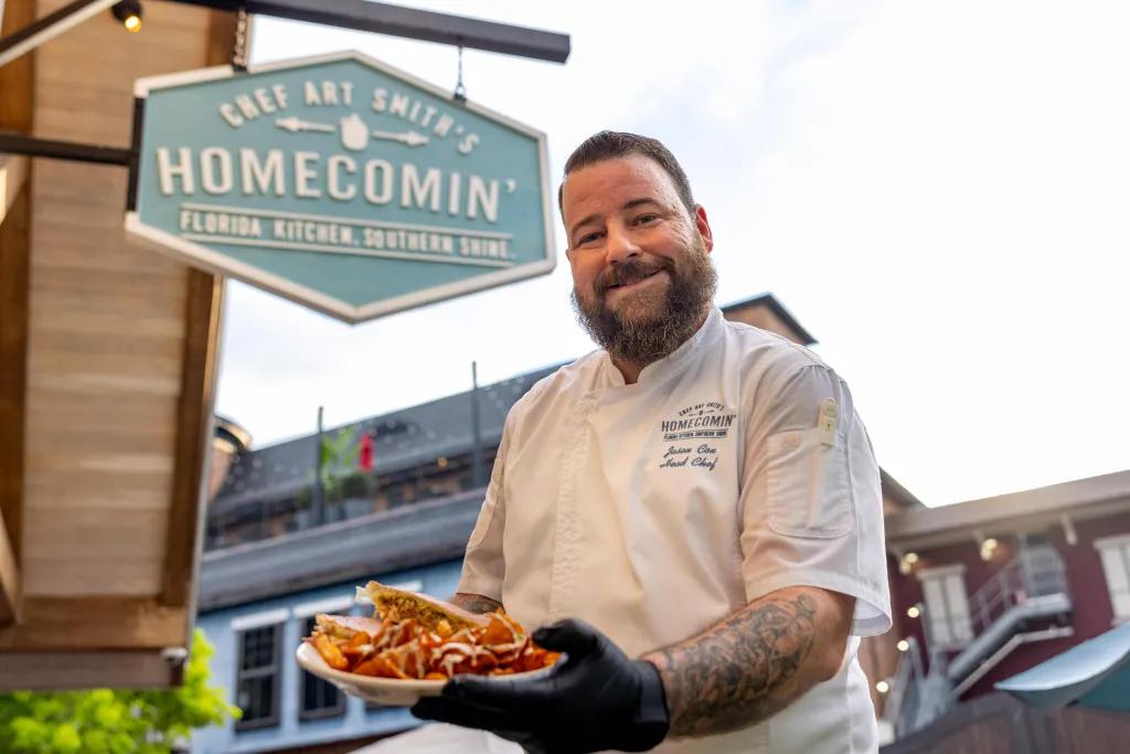 Flavours of Florida at Chef Art Smith's Homecomin' A chef holding a plate of food and smiling at the camera