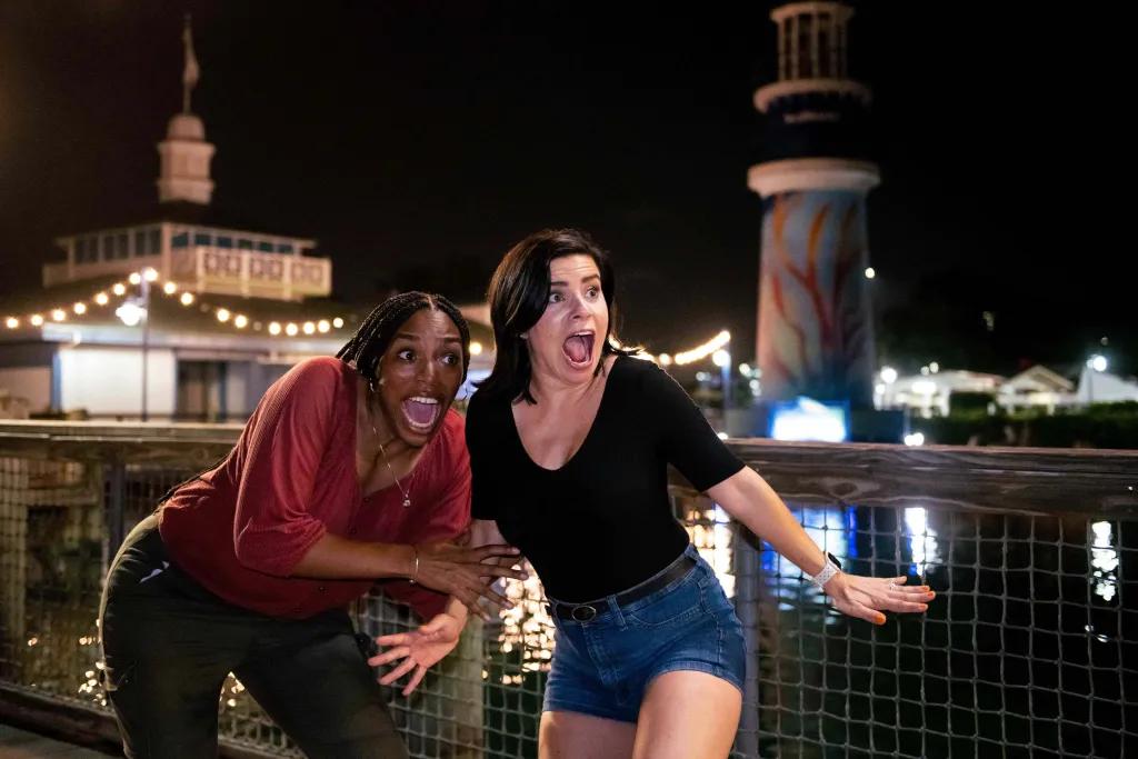 SeaWorld scare zone Two women clutching onto one another and screaming at something off camera with a large lake and the iconic SeaWorld lighthouse in the background.