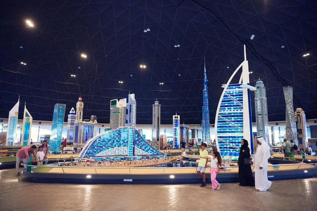 LEGOLAND Dubai A family walking through lego sculptures of iconic Dubai skyscrapers including the Burj Al Arab and Jumeirah hotel next door.