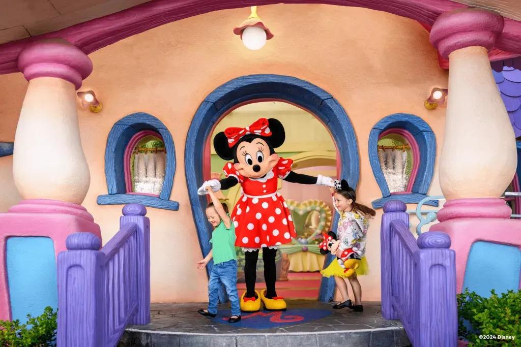 Kinder tanzen mit Minnie Zwei kleine Mädchen tanzen mit Minnie auf den Stufen ihres Hauses in Disneyland