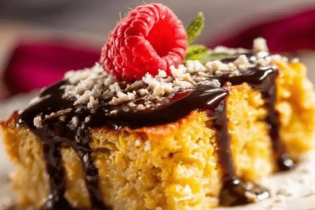 Mexico Menu Yellow coloured cake with chocolate sauce dripping down and white powder on top. There is also a raspberry on top and some green leaves.