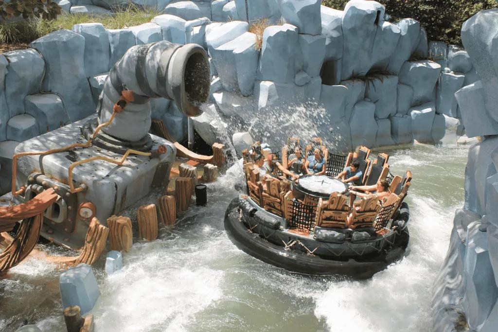 Popeye & Bluto’s Bilge Rat Barges 12 people sat in circular raft with wooden seats, going along river rapids surrounded by stone walls and getting splashed from fountains.