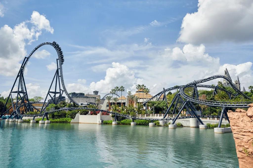 VelociCoaster in Universal Islands of Adventure A pristine blue lake with a tall rollercoaster towering in the background. It is grey and features a huge drop and many twists and turns.