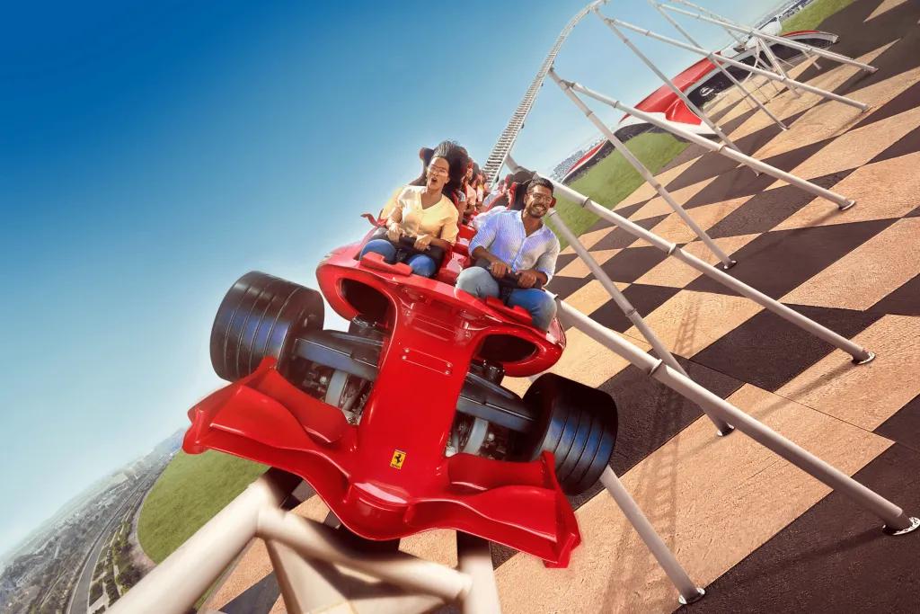 Formula Rossa Two adults on a high speed rollercoaster outside of the Ferrari red building on a coaster car shaped like a red Formula 1 car.