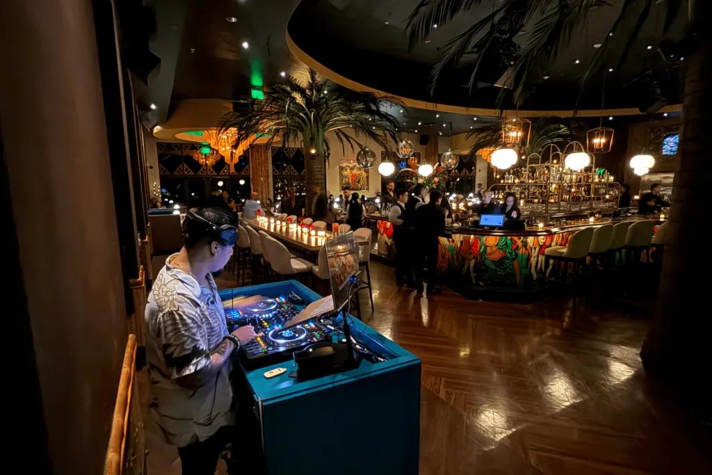 Corazón by Baires, image by Matt Roseboom The dimly lit restaurant with a man stood behind a turquoise dj deck wearing headphones. In front there is a small dancefloor space and the tables are in the background.