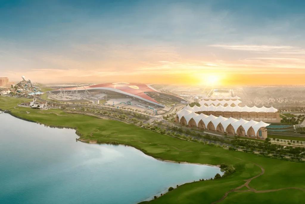 Ferrari World Sun setting over the Ferrari World complex. A large building with the yellow Ferrari logo and the f1 circuit. There is also a lake.
