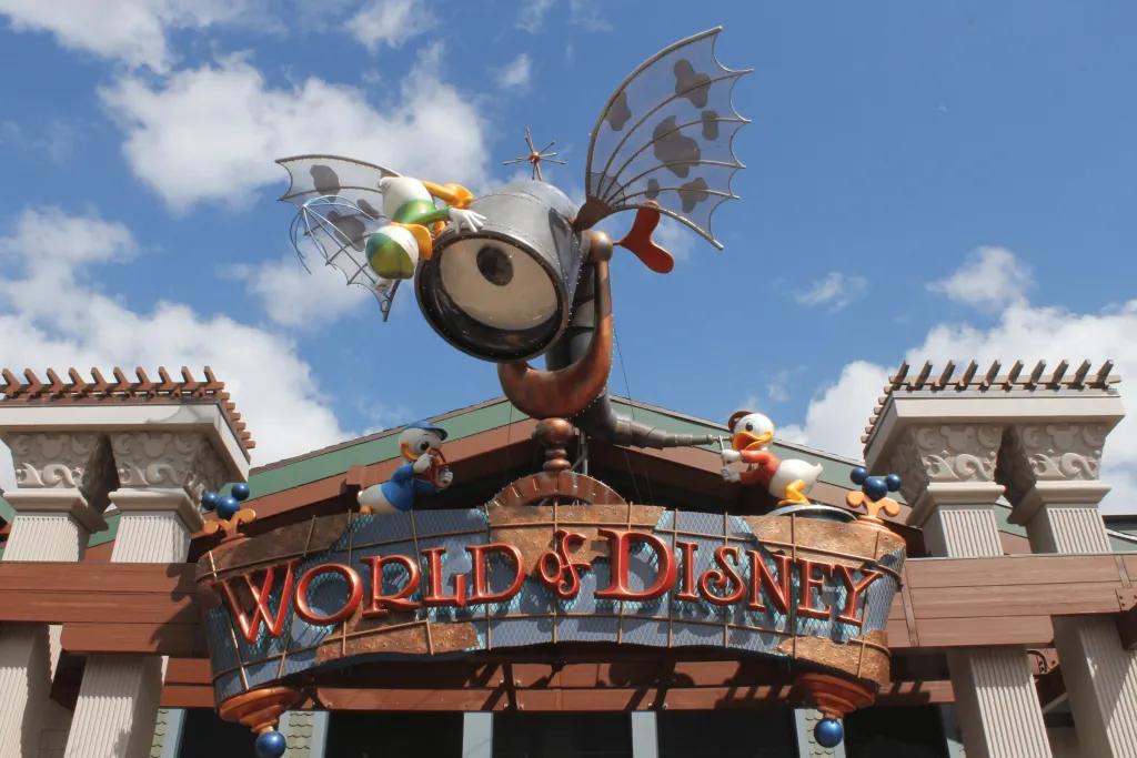 World of Disney There is a large shop with a huge wooden sign saying World of Disney in red. There is a cartoon sculpture of an eye looking through a telescope.