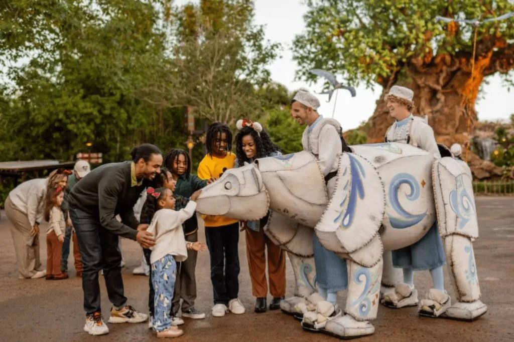 Disney's Animal Kingdom Theme Park Two people dressed up in white costume with a huge polar bear puppet attached to them in front of the tree of life. There are kids petting the polar bear and the parents are crouched down smiling.