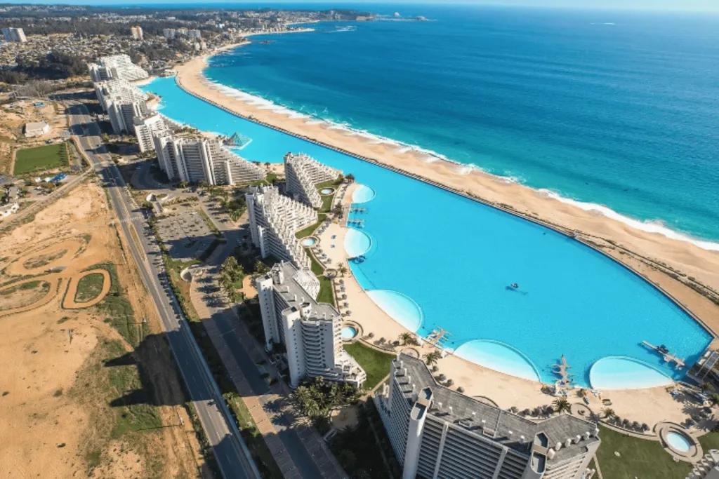 San Alfonso del Mar in Chile There is a huge hotel complex behind a huge swimming pool which lines up with the coastline and sea on the other side of it. The pool is considered the world's largest swimming pool, stretching 20-acres long.