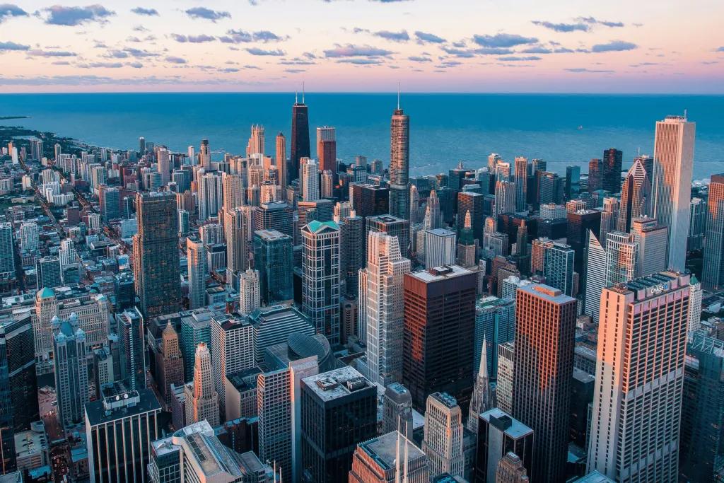 Chicago A large city full of tightly packed skyscrapers, coloured white and brown, glowing as the sunsets. In the background, you can see the sea as this is city is on the coast.