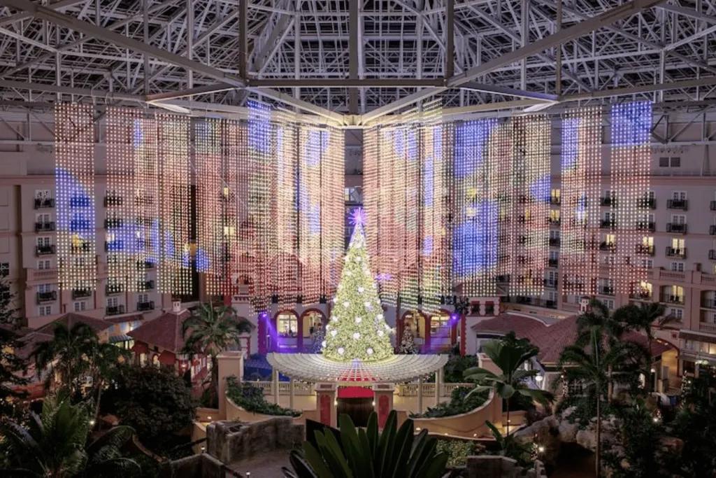 Christmas tree at Gaylord Palms Resort There is a giant room with doors to the rooms showing, with about 7 floors. In the centre, there is a giant Christmas tree lit in gold lighting and a star on top. Either side of the tree there are sheets of lights hanging from the ceiling.