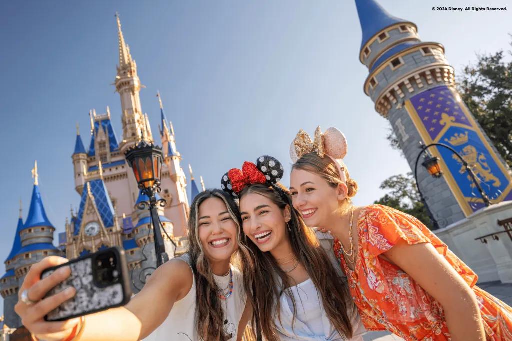 Cinderella Castle at Magic Kingdom Park Three girls in front of Cinderella Castle in Magic Kingdom Park (big blue and pink pastel coloured castle). They are wearing different mickey ear headbands on their heads.