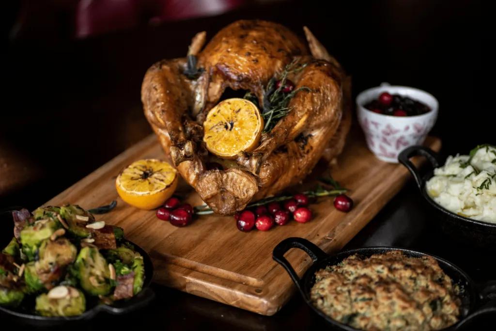 Raglan Road Christmas Roast chicken on a wooden board and there are sides such as mashed potato, vegetables and mac and cheese
