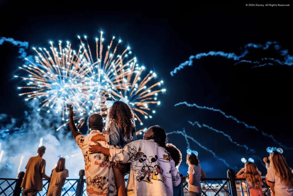 Walt Disney World Resort in Florida Family of three, with two parents holding up their little girl to see the fireworks in the sky better.
